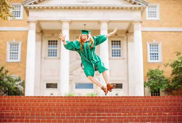 Person wearing graduation gown jumping